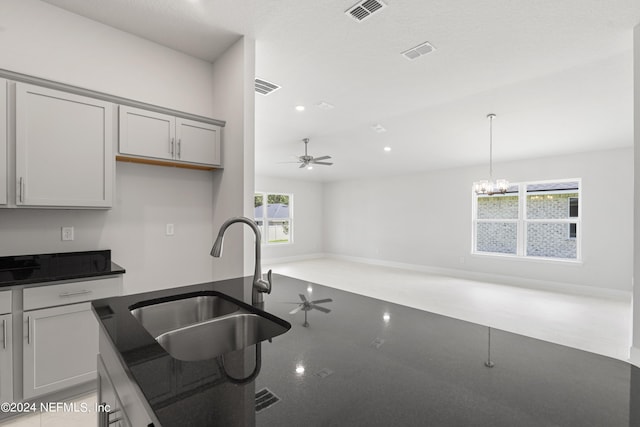 kitchen featuring pendant lighting, ceiling fan with notable chandelier, gray cabinets, and sink