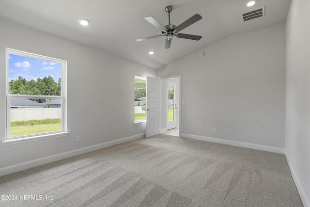 spare room featuring ceiling fan, lofted ceiling, and light carpet