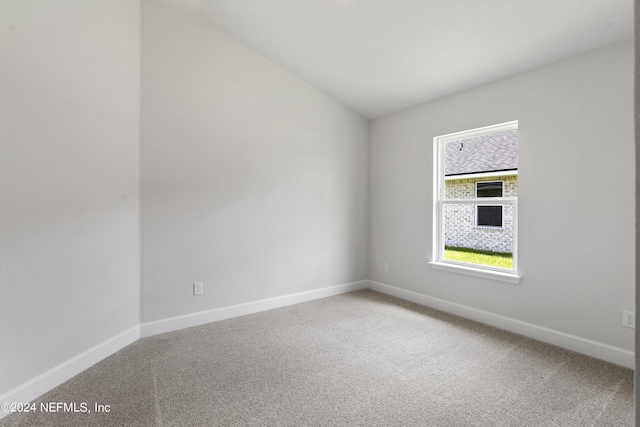 spare room featuring carpet and lofted ceiling