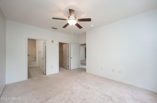 unfurnished bedroom with ensuite bath, ceiling fan, and light carpet