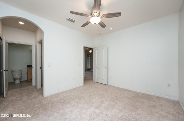 unfurnished bedroom with ceiling fan, light colored carpet, and ensuite bath