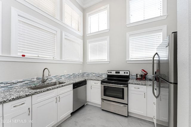 kitchen featuring light stone countertops, sink, stainless steel appliances, crown molding, and white cabinets