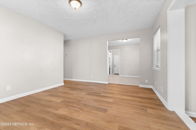 empty room featuring a textured ceiling and light hardwood / wood-style flooring