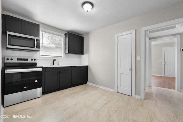 kitchen with backsplash, sink, a textured ceiling, and appliances with stainless steel finishes