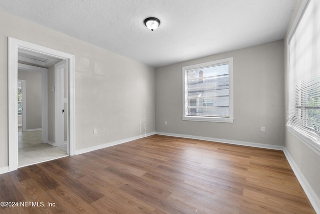 spare room featuring a healthy amount of sunlight, wood-type flooring, and a textured ceiling