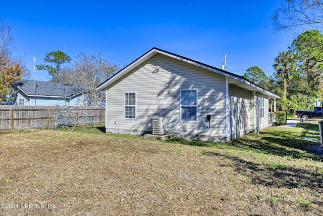 rear view of property featuring a yard and central air condition unit