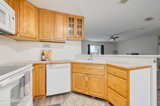 kitchen with kitchen peninsula, a textured ceiling, white appliances, ceiling fan, and sink