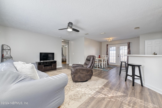 living room with hardwood / wood-style floors, ceiling fan, a textured ceiling, and french doors