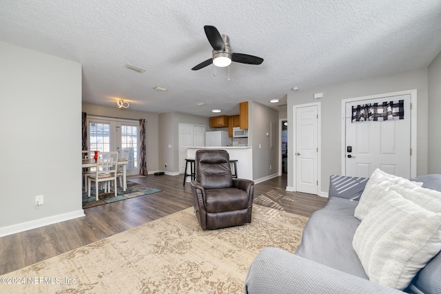 living room with a textured ceiling, dark hardwood / wood-style flooring, and ceiling fan