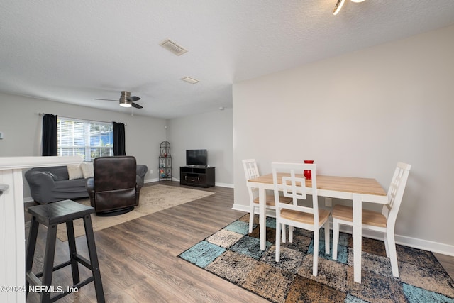 dining area with ceiling fan, wood-type flooring, and a textured ceiling