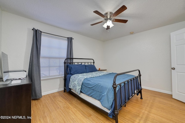 bedroom with ceiling fan, light hardwood / wood-style floors, and a textured ceiling