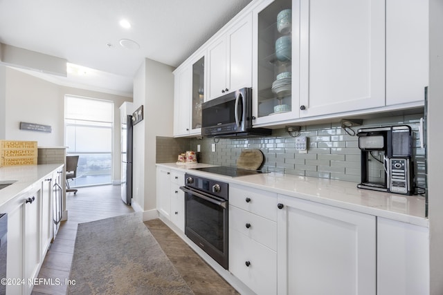 1431 Riverplace Blvd Unit 2105, Jacksonville, FL 32207 - kitchen with glass insert cabinets, tasteful backsplash, black appliances, and white cabinets