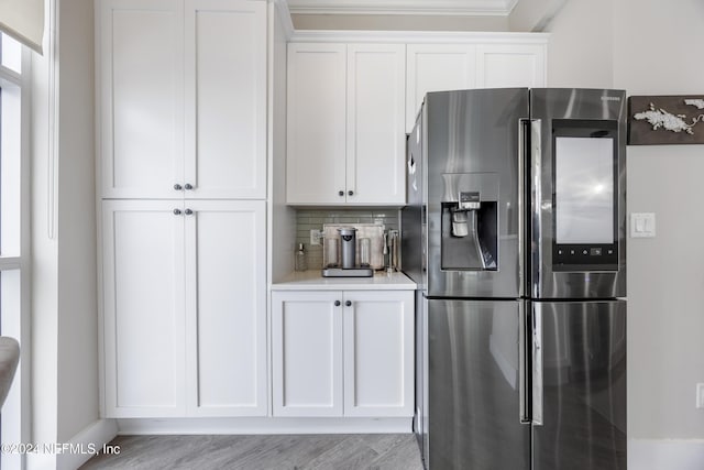 1431 Riverplace Blvd Unit 2105, Jacksonville, FL 32207 - kitchen featuring light wood-style flooring, light countertops, white cabinets, stainless steel fridge, and tasteful backsplash