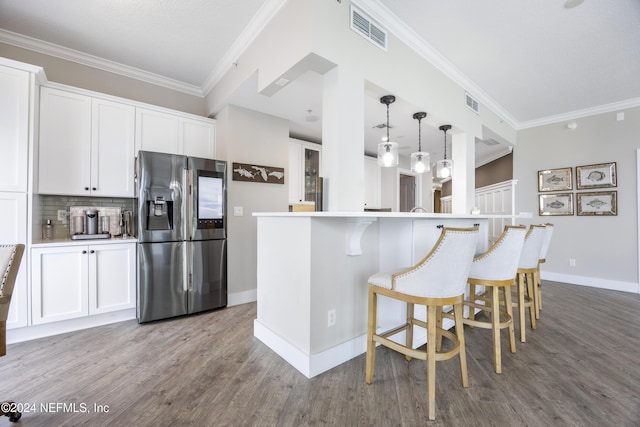 1431 Riverplace Blvd Unit 2105, Jacksonville, FL 32207 - kitchen with visible vents, backsplash, stainless steel fridge, a breakfast bar area, and white cabinets