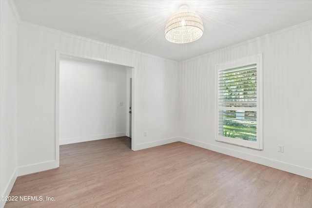 spare room featuring crown molding, light hardwood / wood-style flooring, and a chandelier