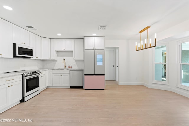 kitchen featuring appliances with stainless steel finishes, sink, light hardwood / wood-style flooring, white cabinetry, and hanging light fixtures