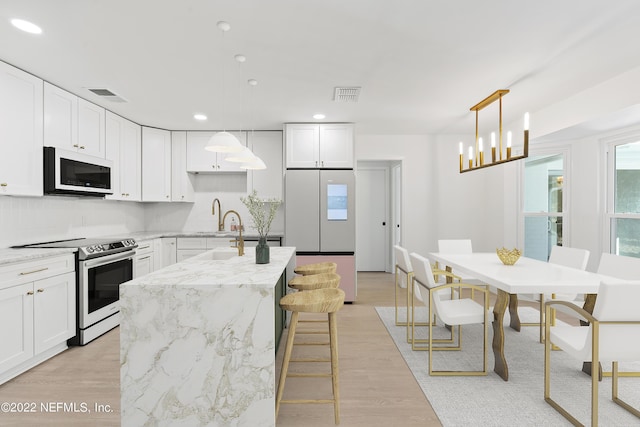 kitchen with white cabinets, pendant lighting, light stone counters, and stainless steel range with electric stovetop