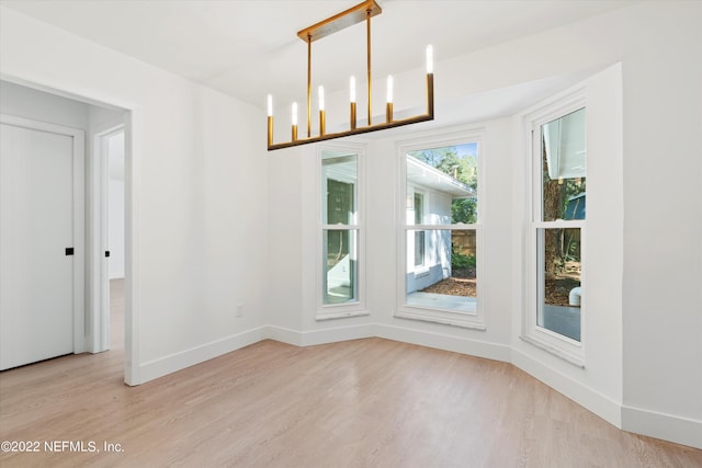 unfurnished dining area featuring a notable chandelier and light wood-type flooring