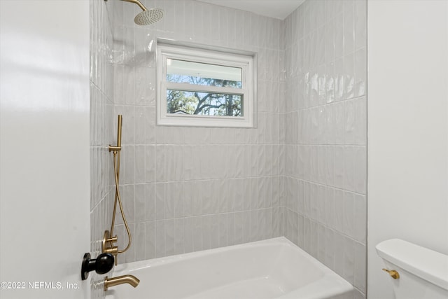 bathroom with tiled shower / bath combo and toilet