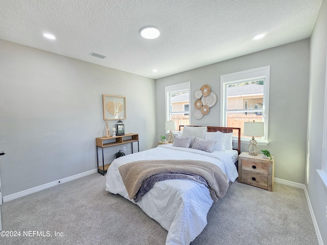 bedroom with a textured ceiling and light colored carpet