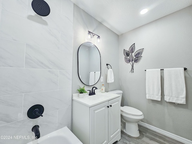 full bathroom featuring hardwood / wood-style floors, vanity, tiled shower / bath combo, toilet, and a textured ceiling