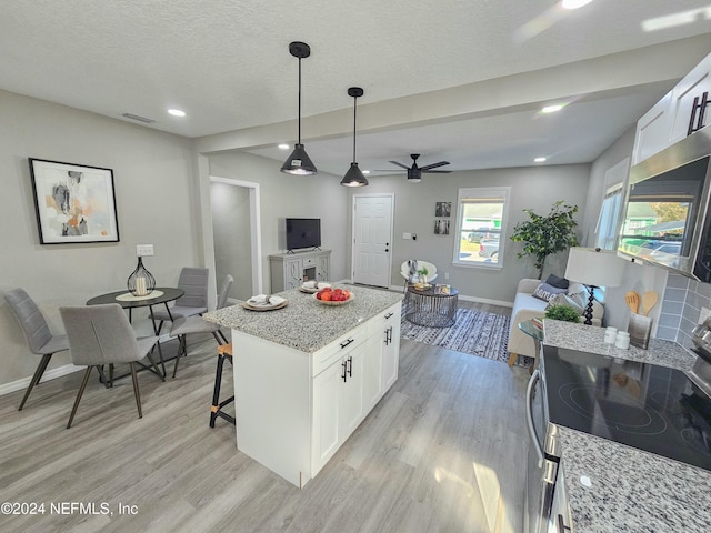 kitchen featuring light wood-type flooring, white cabinetry, light stone counters, and stainless steel range