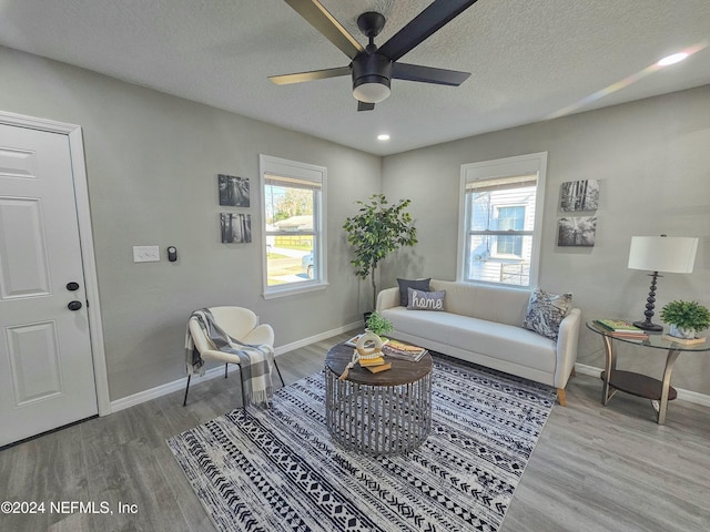 living room featuring ceiling fan, a textured ceiling, and hardwood / wood-style flooring