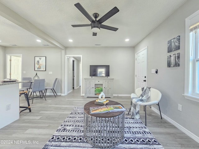 living room featuring light wood-type flooring, plenty of natural light, and ceiling fan