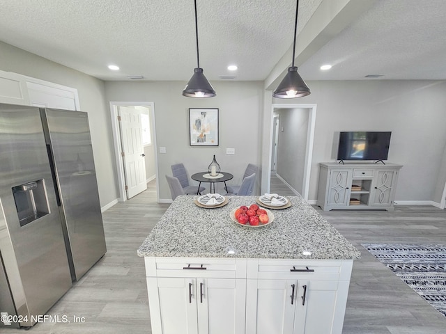 kitchen with white cabinets, stainless steel refrigerator with ice dispenser, light stone counters, and hanging light fixtures