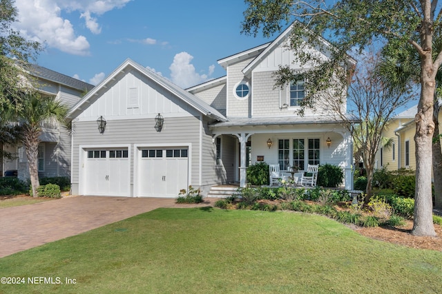 view of front of house with covered porch, a garage, and a front yard