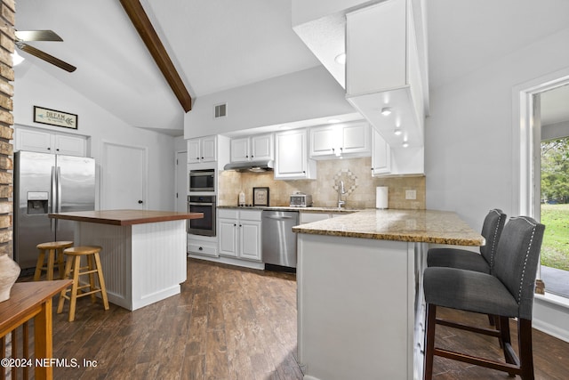 kitchen with kitchen peninsula, stainless steel appliances, white cabinetry, and a breakfast bar area