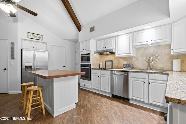 kitchen featuring beamed ceiling, white cabinets, stainless steel appliances, and a kitchen island