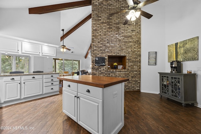 kitchen featuring high vaulted ceiling, beamed ceiling, white cabinets, a center island, and butcher block counters