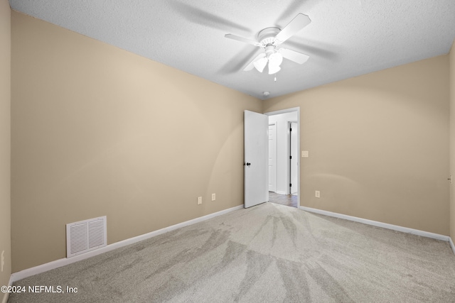 spare room featuring light carpet, ceiling fan, and a textured ceiling