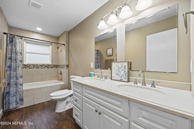 full bathroom featuring shower / bath combo, vanity, a textured ceiling, hardwood / wood-style floors, and toilet