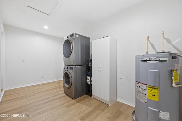 laundry area with light hardwood / wood-style floors, stacked washer / dryer, and water heater