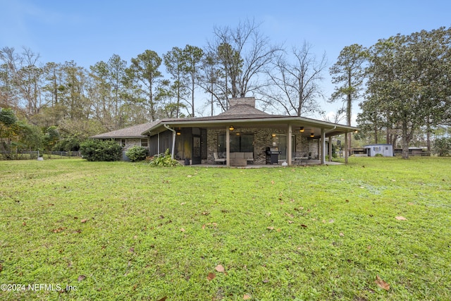 rear view of property featuring ceiling fan, a storage unit, and a yard