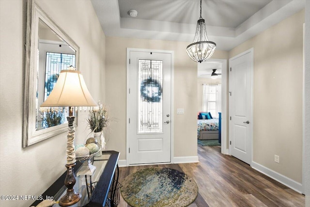 foyer with a chandelier, dark hardwood / wood-style flooring, and a raised ceiling