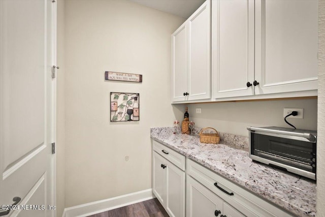 interior space featuring white cabinetry, dark wood-type flooring, and light stone counters