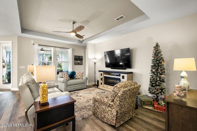 living room featuring hardwood / wood-style floors, a tray ceiling, and ceiling fan