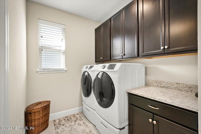 clothes washing area featuring cabinets, light tile patterned floors, and washing machine and clothes dryer