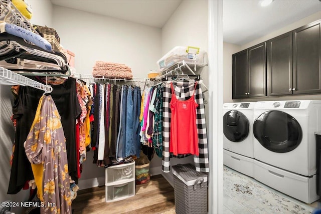 laundry area with separate washer and dryer, light hardwood / wood-style flooring, and cabinets