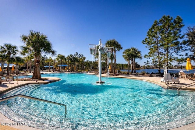 view of swimming pool featuring a patio and a water view