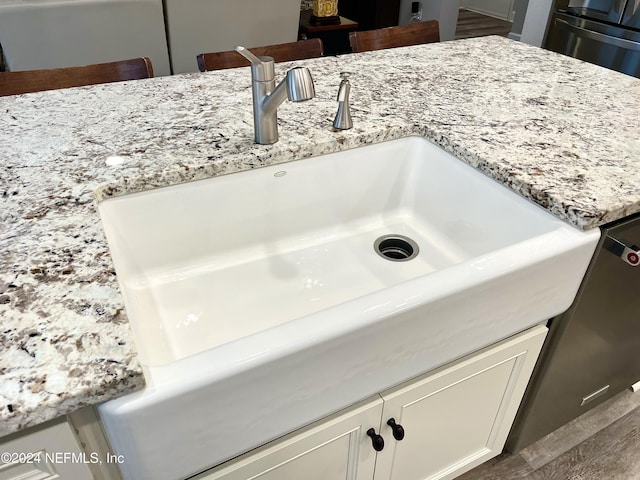 room details with light stone counters, white cabinetry, and sink