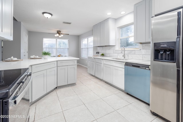 kitchen with backsplash, stainless steel appliances, ceiling fan, sink, and light tile patterned floors