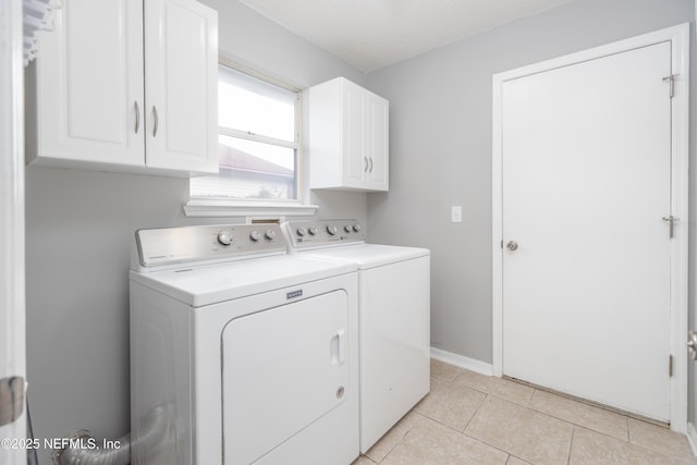 washroom featuring separate washer and dryer, light tile patterned floors, and cabinets