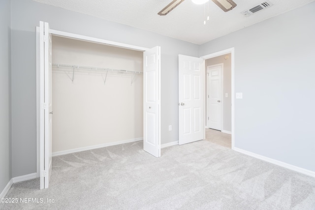 unfurnished bedroom featuring a textured ceiling, ceiling fan, light carpet, and a closet