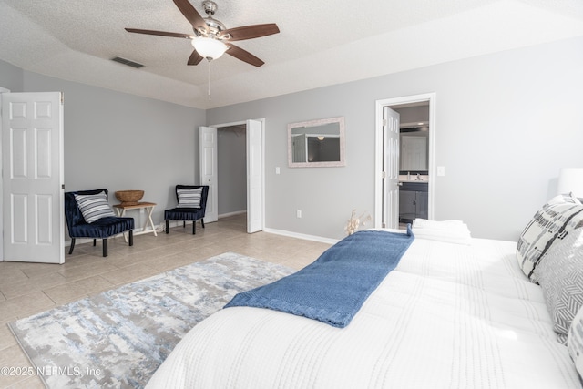 tiled bedroom featuring ceiling fan, a raised ceiling, ensuite bathroom, and a textured ceiling