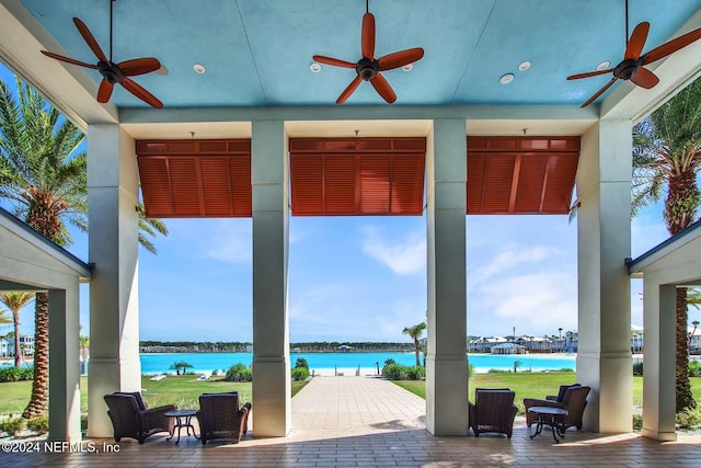 view of patio with a water view and ceiling fan