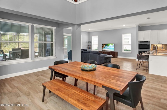 dining room featuring sink, light hardwood / wood-style floors, and ornamental molding